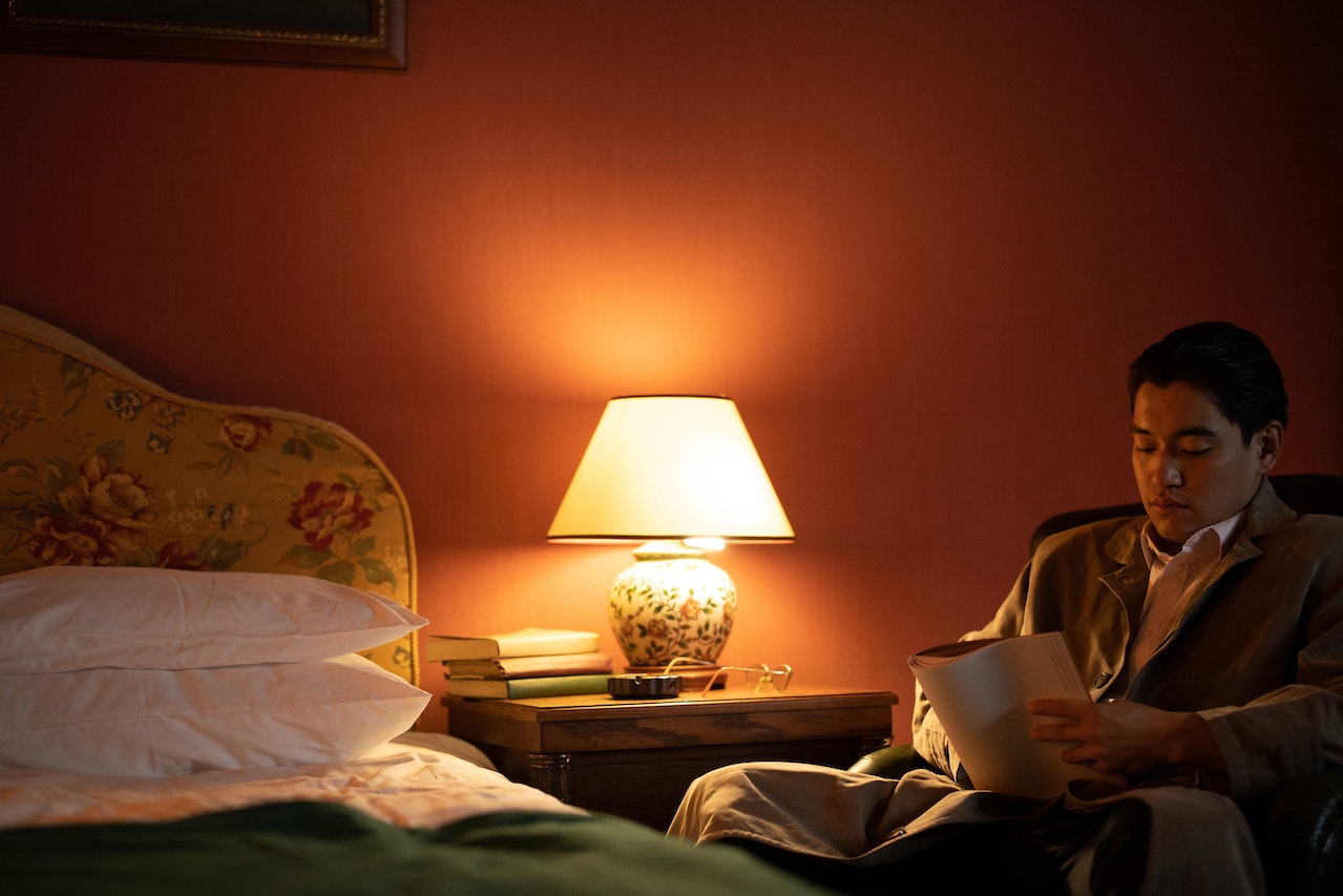 Man is using his night lamp to read a book